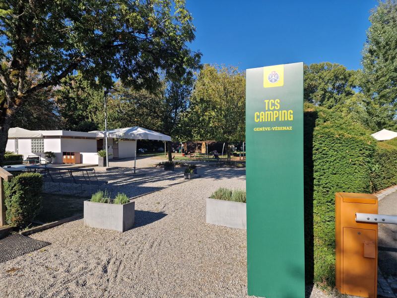 Grüne Stele mit der Aufschrift TCS Camping Genève-Vésenaz an der Einfahrt