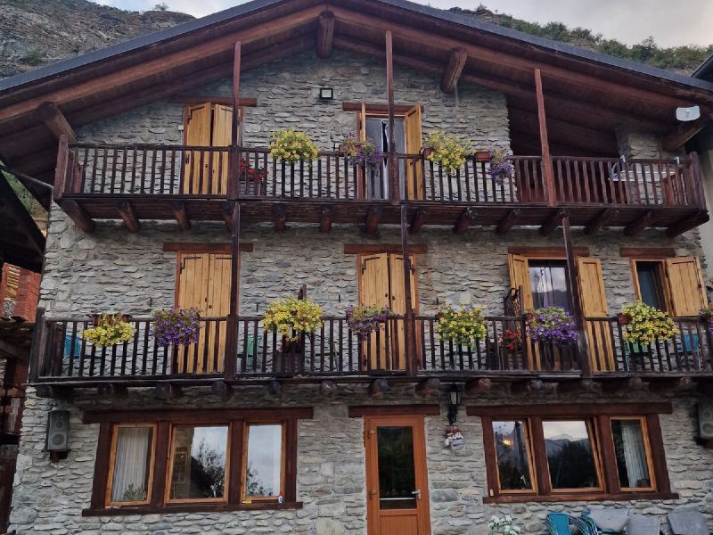 Steinhaus mit Holzbalkonen und Blumenkästen in Venaus